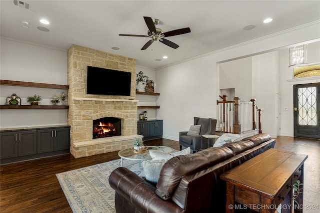 living room featuring ceiling fan, ornamental molding, dark hardwood / wood-style flooring, and a fireplace