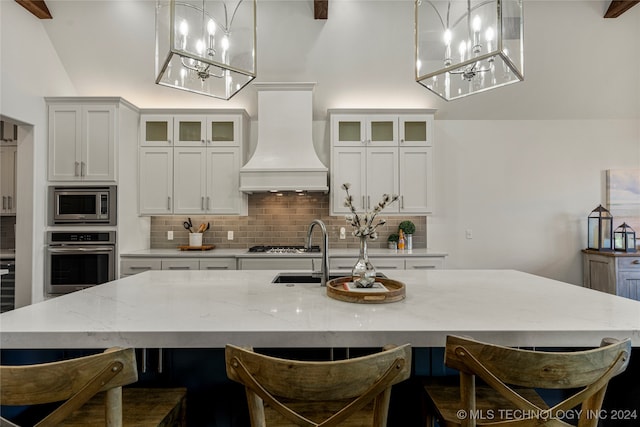 kitchen featuring white cabinets, pendant lighting, custom exhaust hood, appliances with stainless steel finishes, and tasteful backsplash