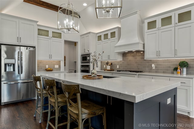 kitchen with backsplash, a center island, white cabinetry, stainless steel appliances, and premium range hood