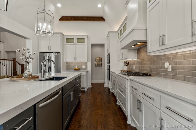 kitchen with vaulted ceiling with beams, custom range hood, stainless steel appliances, decorative light fixtures, and white cabinets