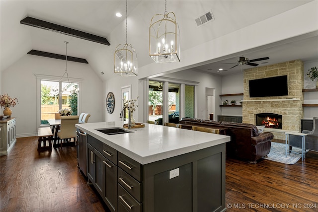 kitchen with a kitchen island with sink, dark hardwood / wood-style floors, hanging light fixtures, sink, and a fireplace