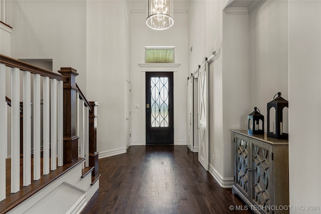 foyer with a chandelier, dark wood-type flooring, a barn door, and a high ceiling