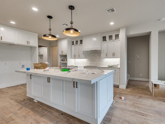 kitchen featuring an island with sink, white cabinetry, light hardwood / wood-style floors, and pendant lighting