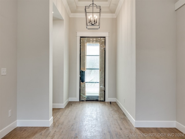 foyer with an inviting chandelier, light hardwood / wood-style flooring, ornamental molding, and a tray ceiling