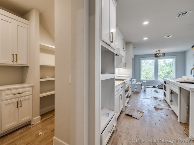 kitchen featuring white cabinets, light wood-type flooring, and sink