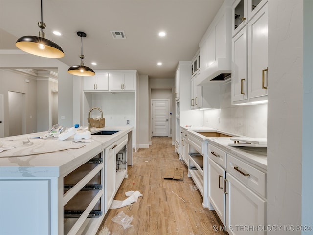 kitchen featuring pendant lighting, white cabinetry, light hardwood / wood-style floors, and sink