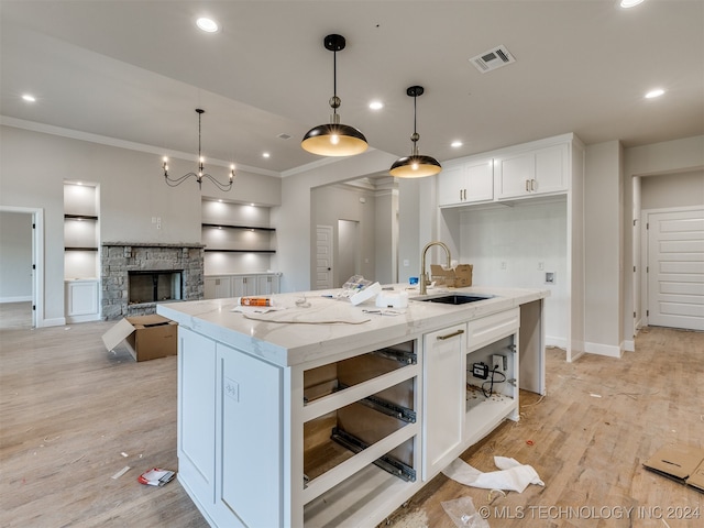 kitchen featuring an island with sink, white cabinetry, pendant lighting, and sink