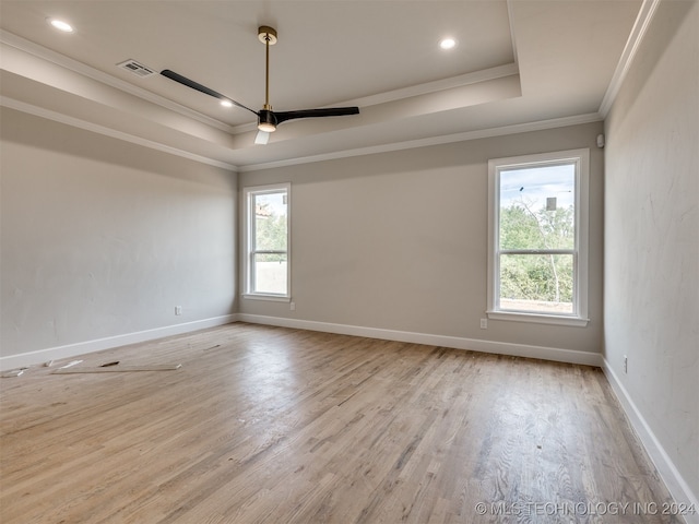 spare room featuring light hardwood / wood-style floors, a raised ceiling, ceiling fan, and crown molding