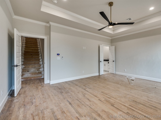 spare room featuring a raised ceiling, light hardwood / wood-style floors, ornamental molding, and ceiling fan