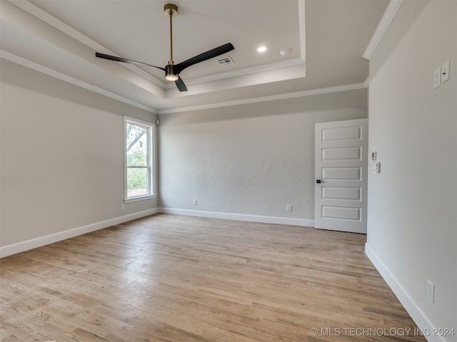 empty room featuring ceiling fan, light hardwood / wood-style flooring, crown molding, and a raised ceiling