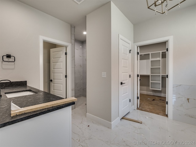 bathroom with vanity, a chandelier, and a tile shower