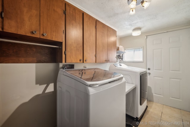 laundry area featuring cabinets, a textured ceiling, light tile patterned floors, and washer and dryer