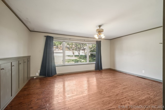 unfurnished room with a notable chandelier, hardwood / wood-style flooring, and ornamental molding