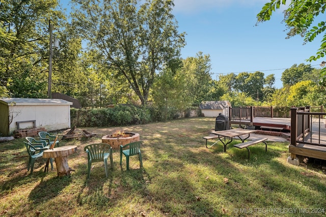 view of yard featuring a storage unit, a wooden deck, and a fire pit