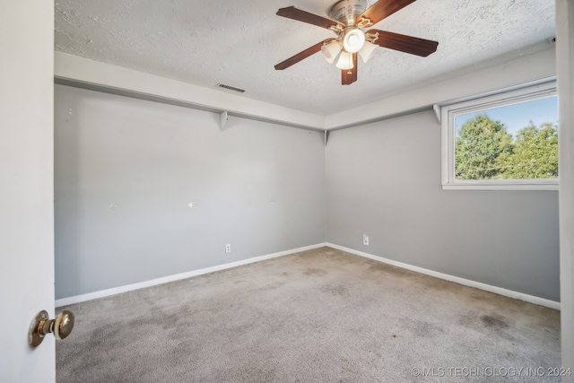 unfurnished room with ceiling fan, carpet flooring, and a textured ceiling