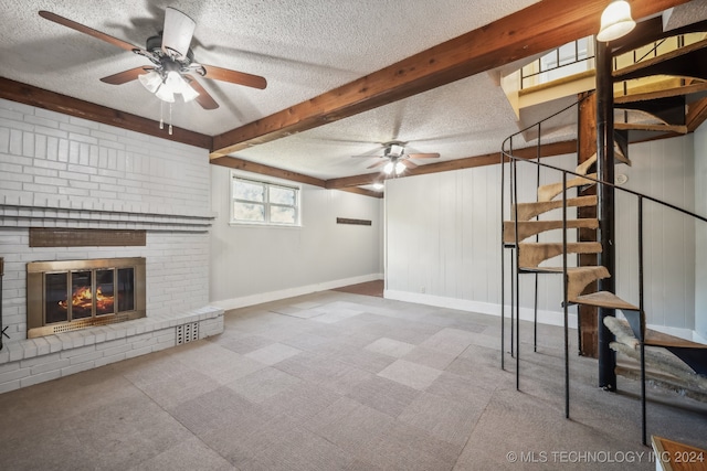 unfurnished living room with a textured ceiling, beamed ceiling, and a brick fireplace