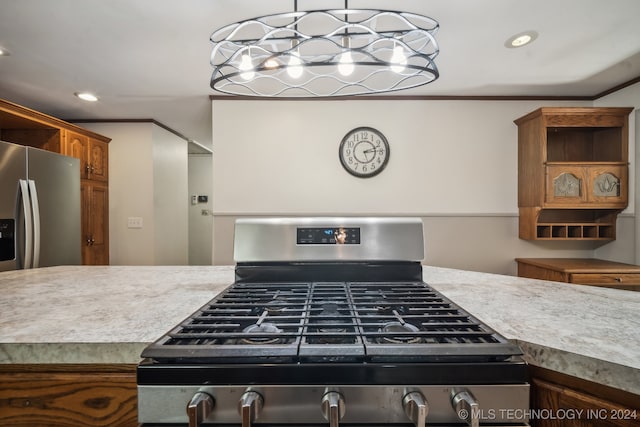 kitchen with appliances with stainless steel finishes, crown molding, and pendant lighting