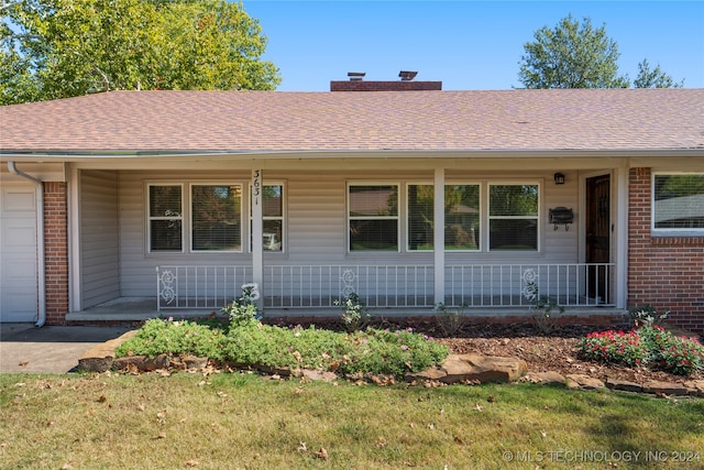 single story home featuring a garage, a front lawn, and covered porch