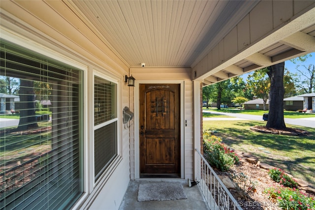 view of exterior entry featuring a lawn