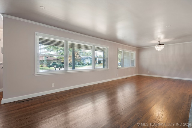 spare room featuring ornamental molding, a notable chandelier, and dark hardwood / wood-style floors