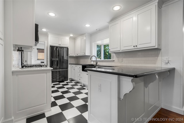 kitchen with sink, kitchen peninsula, white cabinetry, a kitchen breakfast bar, and refrigerator with ice dispenser