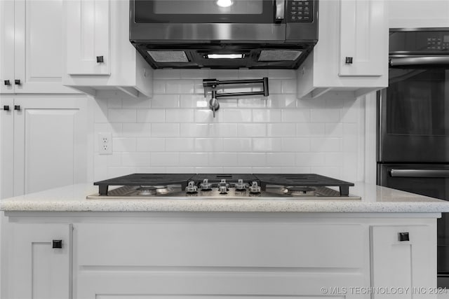 kitchen with decorative backsplash, white cabinetry, light stone counters, stainless steel gas cooktop, and double oven