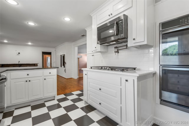 kitchen with stainless steel appliances, white cabinetry, tasteful backsplash, and crown molding