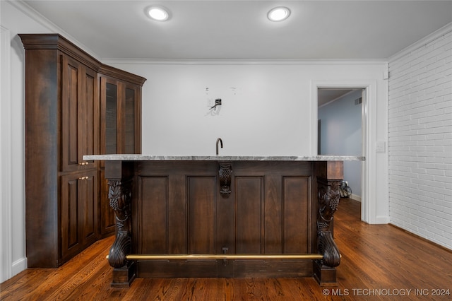 bar featuring dark brown cabinetry, ornamental molding, dark hardwood / wood-style flooring, and brick wall