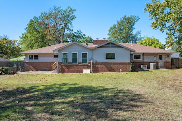 rear view of property featuring a lawn and central air condition unit