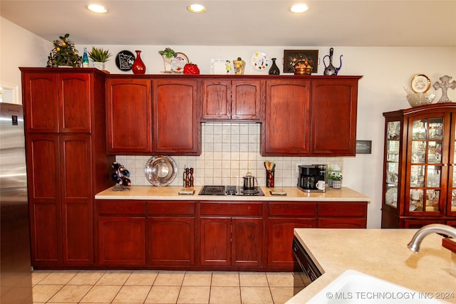 kitchen with dishwasher, sink, gas cooktop, light tile patterned floors, and stainless steel fridge