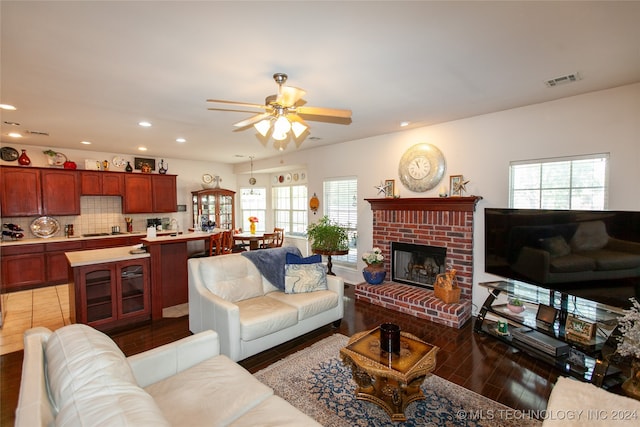 living room featuring a healthy amount of sunlight, a fireplace, dark hardwood / wood-style floors, and ceiling fan