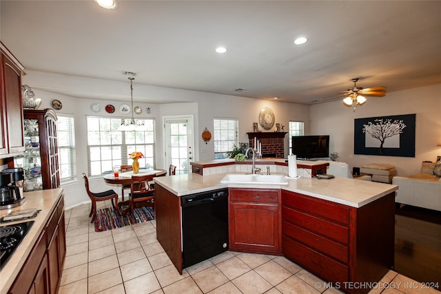 kitchen featuring decorative light fixtures, a center island with sink, sink, and black appliances