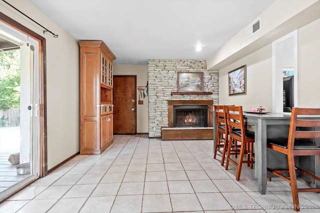 dining room with a stone fireplace and light tile patterned flooring