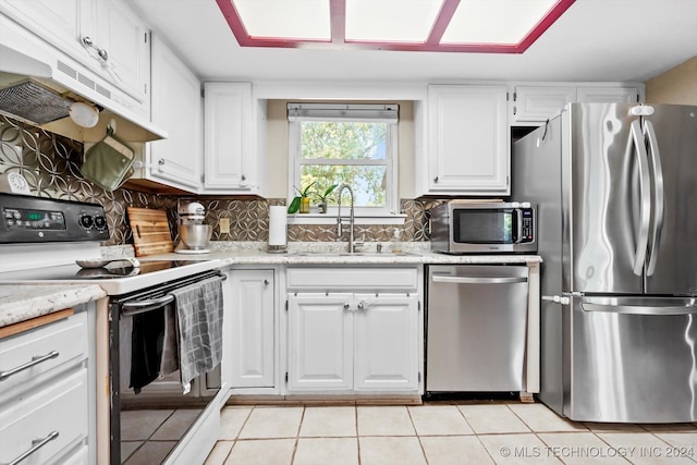 kitchen featuring decorative backsplash, sink, white cabinetry, appliances with stainless steel finishes, and light tile patterned floors