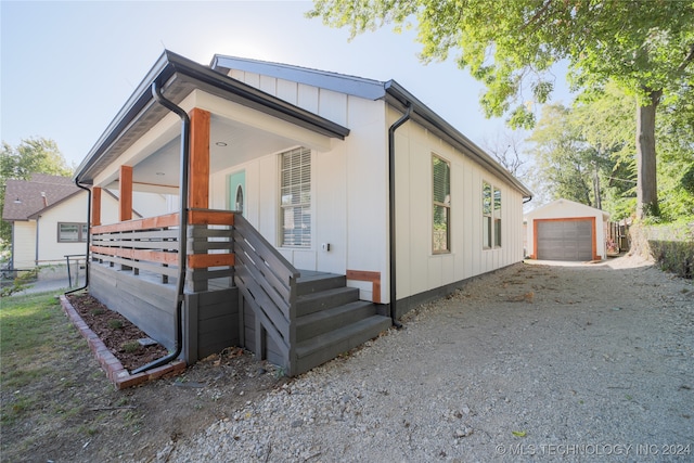 view of property exterior with a porch, a garage, and an outbuilding