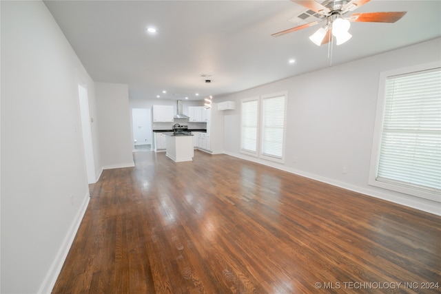 unfurnished living room with an AC wall unit, ceiling fan, dark wood-type flooring, and sink