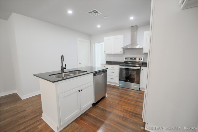 kitchen with white cabinetry, sink, stainless steel appliances, wall chimney range hood, and a kitchen island with sink