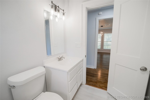 bathroom with hardwood / wood-style floors, vanity, and toilet