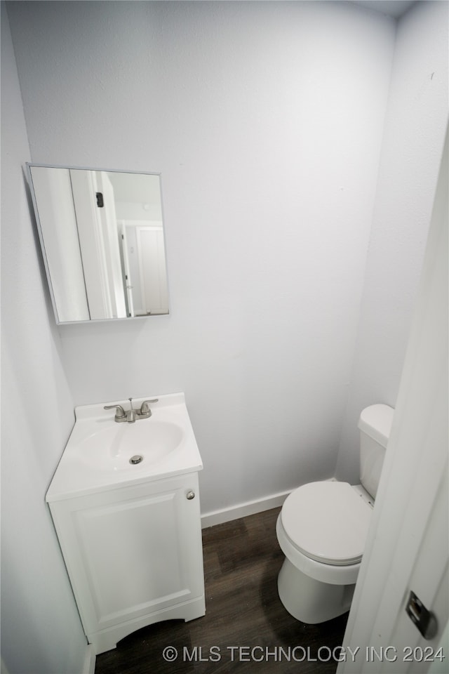 bathroom with toilet, vanity, and hardwood / wood-style flooring