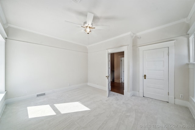 unfurnished bedroom with light carpet, crown molding, ceiling fan, and a closet