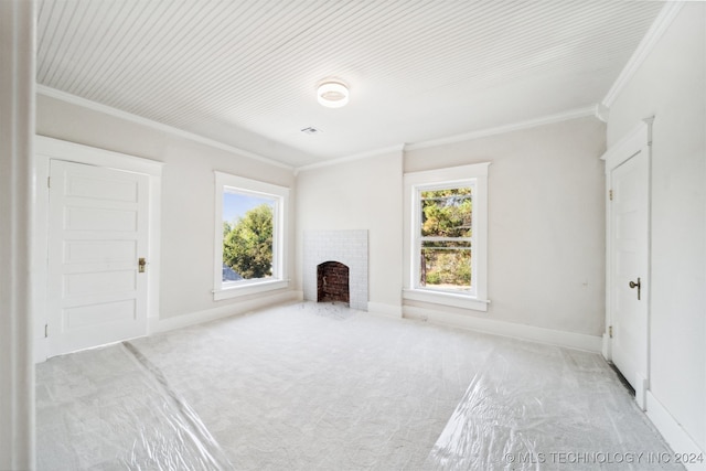 unfurnished living room with a brick fireplace, crown molding, light colored carpet, and a wealth of natural light