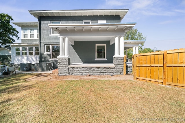 rear view of house featuring a lawn and central AC