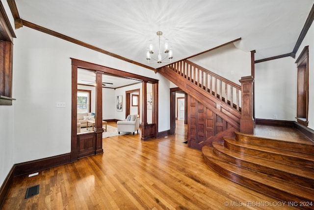 interior space with light wood-type flooring, a notable chandelier, and crown molding