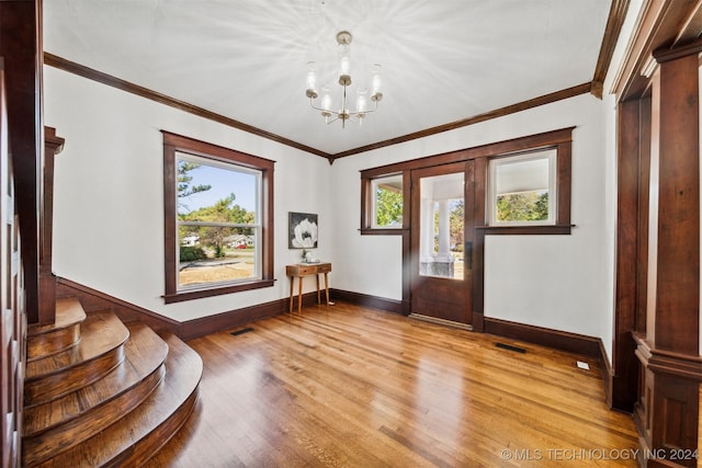 entryway with light hardwood / wood-style floors, crown molding, and a chandelier