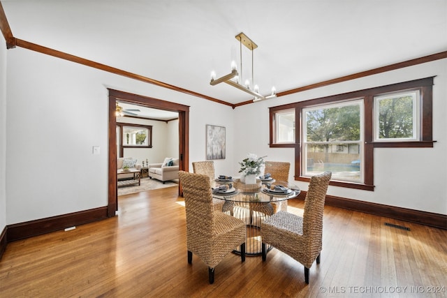 dining room featuring ceiling fan with notable chandelier, crown molding, and light wood-type flooring