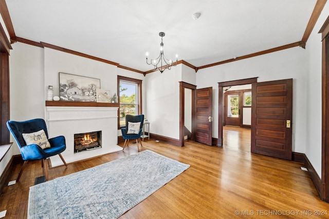 living area featuring ornamental molding, a chandelier, and wood-type flooring