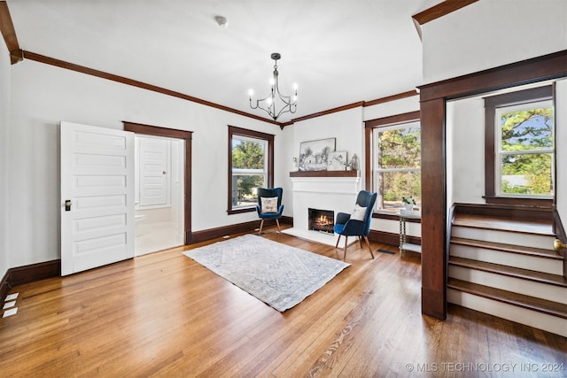 living area with crown molding, a wealth of natural light, a chandelier, and light hardwood / wood-style floors