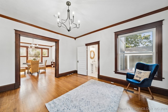 living area featuring ornamental molding, hardwood / wood-style floors, and a notable chandelier