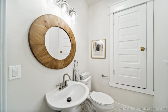 bathroom with toilet, tile patterned flooring, and sink