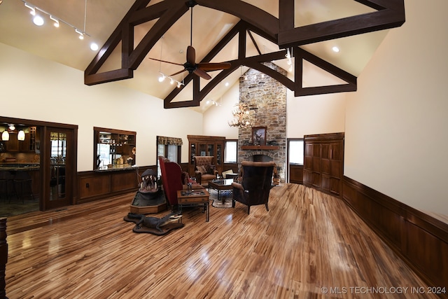 living room featuring ceiling fan, a stone fireplace, hardwood / wood-style floors, and high vaulted ceiling